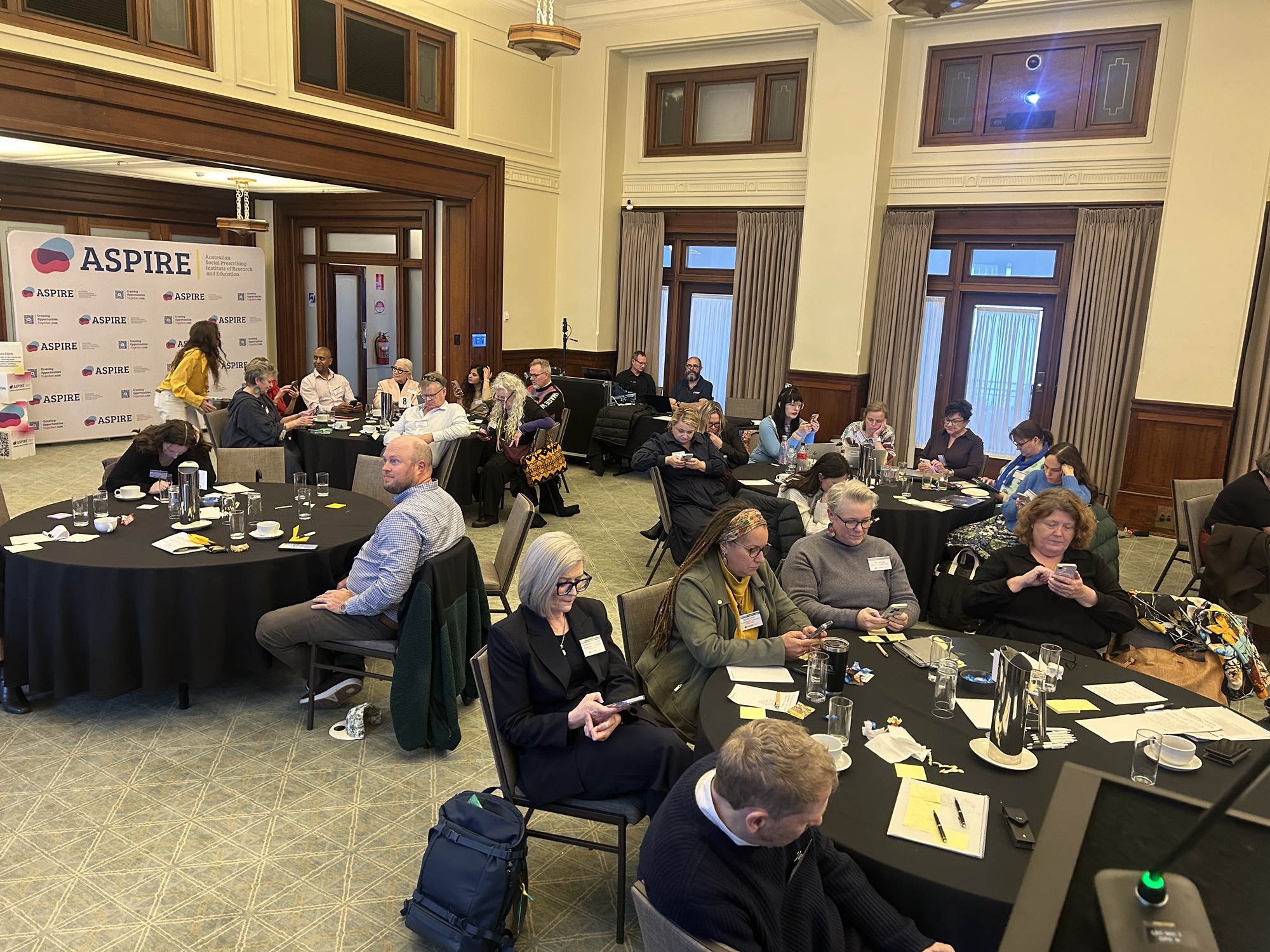 Policy Lab participants deliberating, with ASPIRE signage in the background.