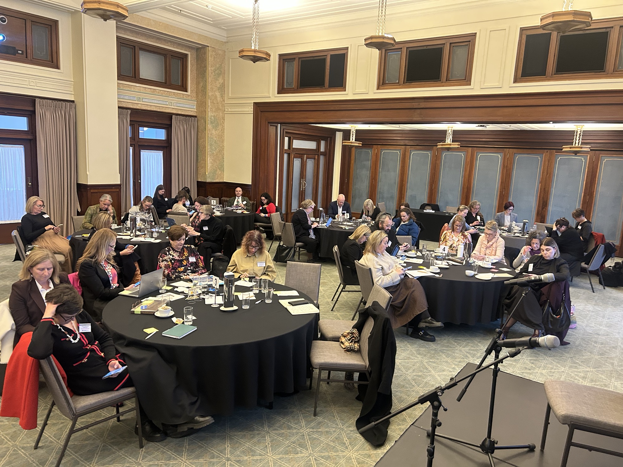 Participants at round tables in the Museum of Australian Democracy voting on their phones during the Policy Lab.